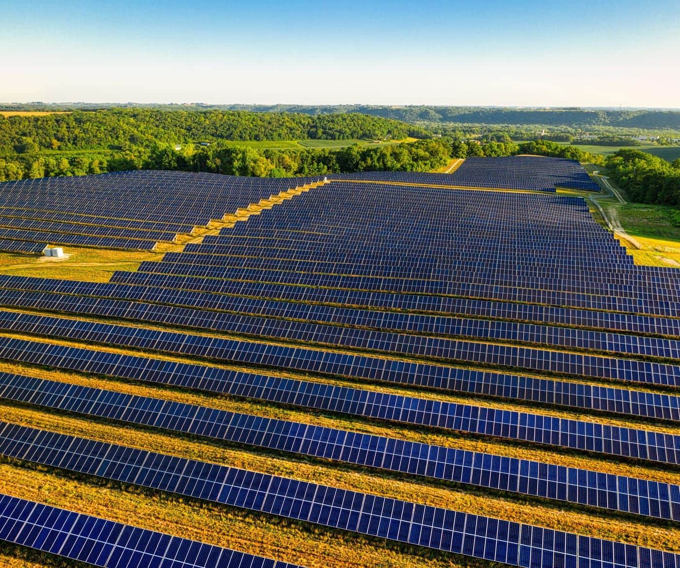Gün batımında sıralar hâlinde uzanan güneş enerjisi santrali panelleri